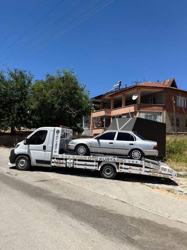 Yerleşim alanında platformunda gümüş otomobil bulunan çekici