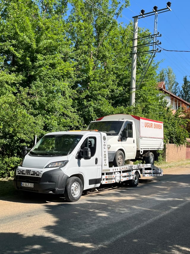 Ağaçlık yol kenarında beyaz ticari araç taşıyan çekici